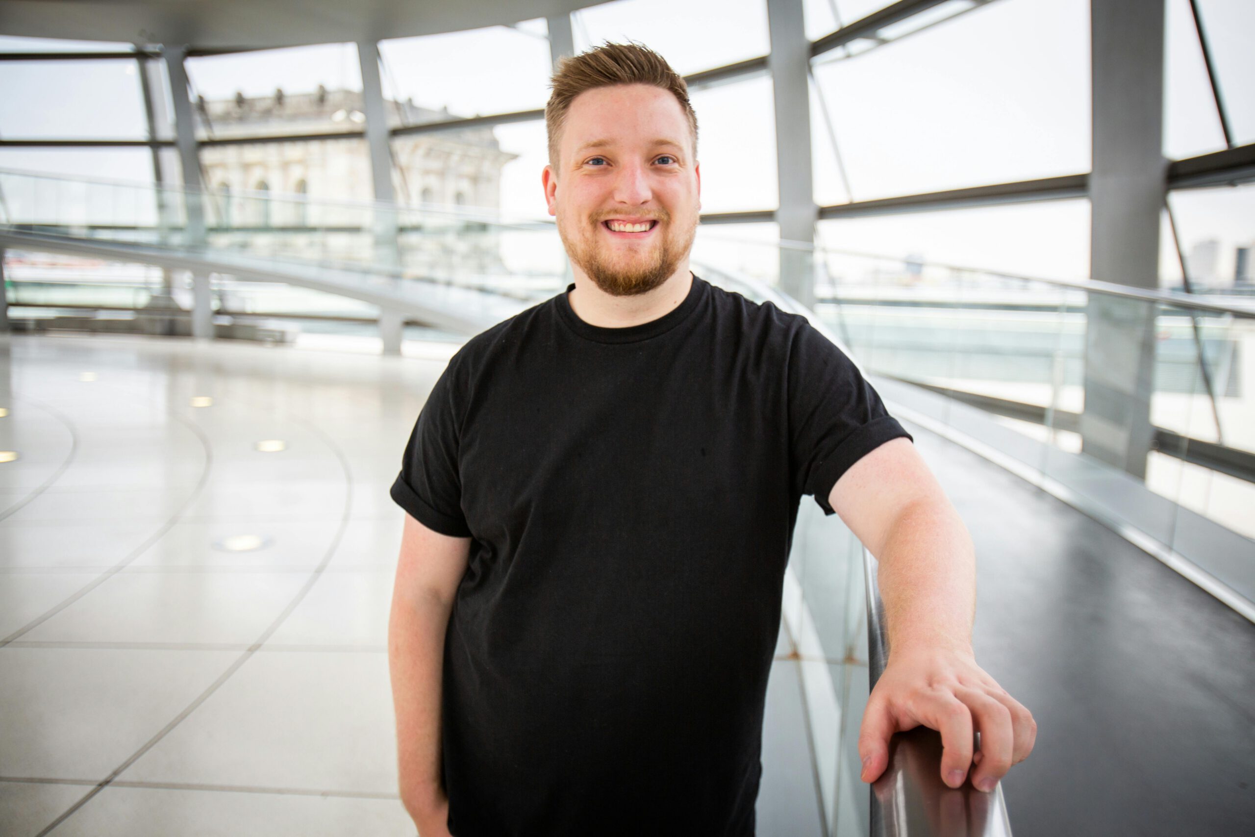 Home Portrait of a smiling man in casual clothing at the Reichstag building in Berlin. Bright and welcoming.